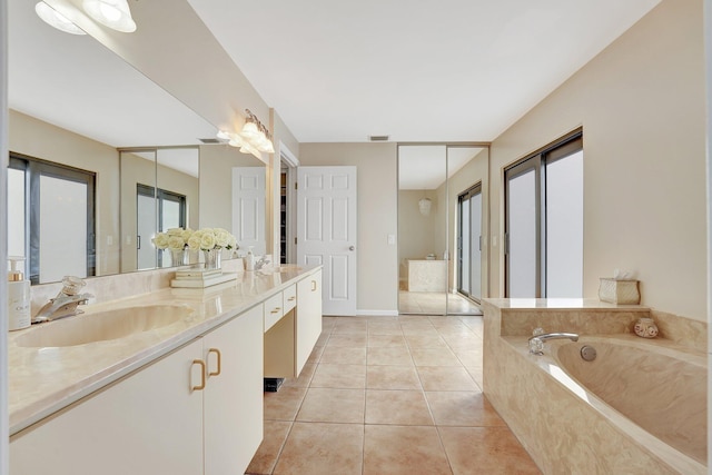 bathroom with tiled tub, vanity, and tile patterned floors