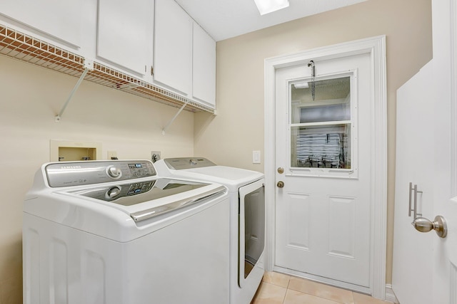 laundry room with cabinets, washing machine and dryer, and light tile patterned floors