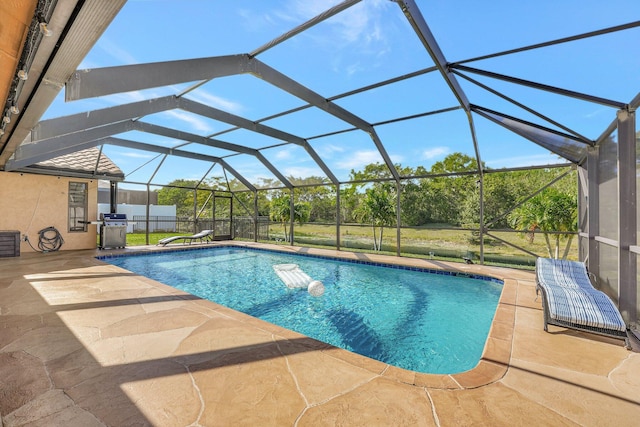 view of swimming pool featuring a lanai, a lawn, grilling area, and a patio area