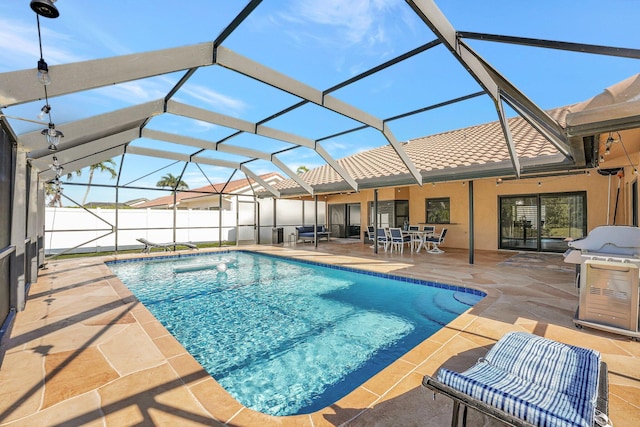 view of swimming pool with a grill, a patio, and glass enclosure