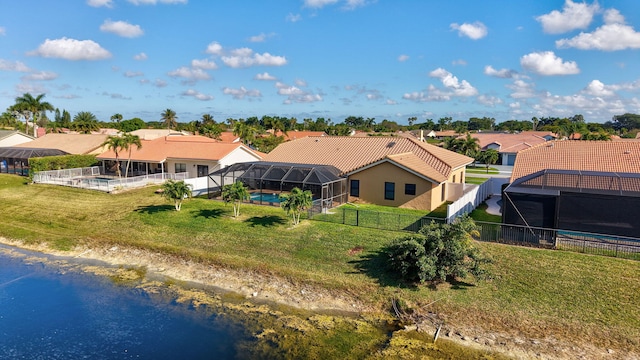 rear view of property featuring a water view, a lanai, a fenced in pool, and a lawn