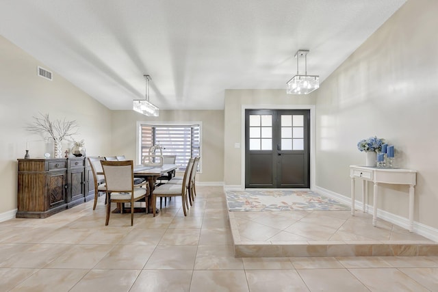 interior space with vaulted ceiling, french doors, a textured ceiling, and light tile patterned flooring