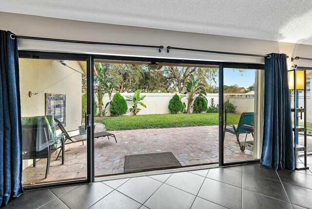 doorway to outside featuring dark tile patterned flooring and a textured ceiling