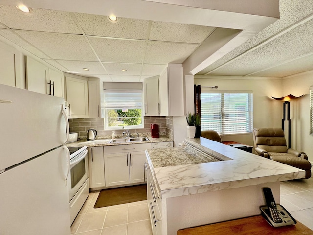 kitchen featuring light tile patterned flooring, white appliances, a healthy amount of sunlight, and sink