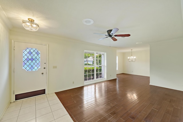 entrance foyer with ceiling fan with notable chandelier, crown molding, baseboards, and wood finished floors