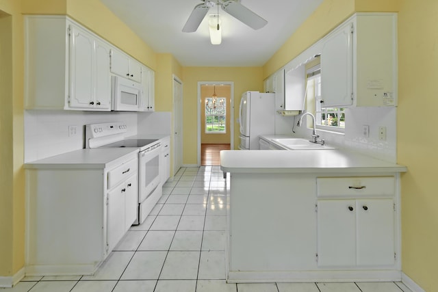 kitchen with a wealth of natural light, white appliances, a peninsula, and a sink