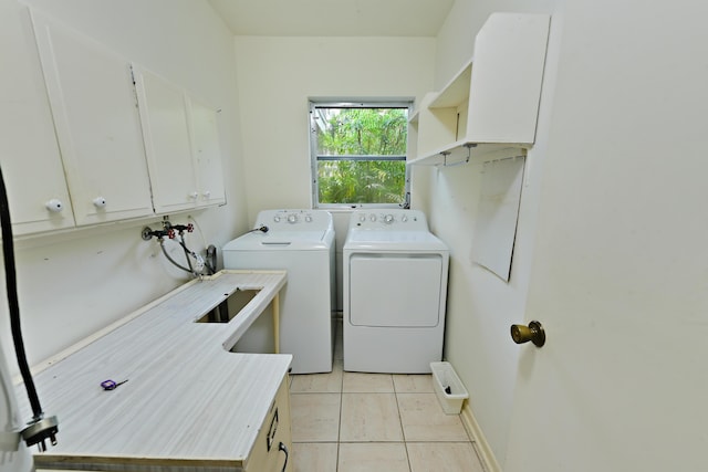 laundry room featuring light tile patterned floors, cabinet space, and washing machine and clothes dryer