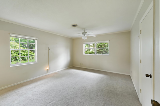 empty room with visible vents, ornamental molding, carpet flooring, baseboards, and ceiling fan