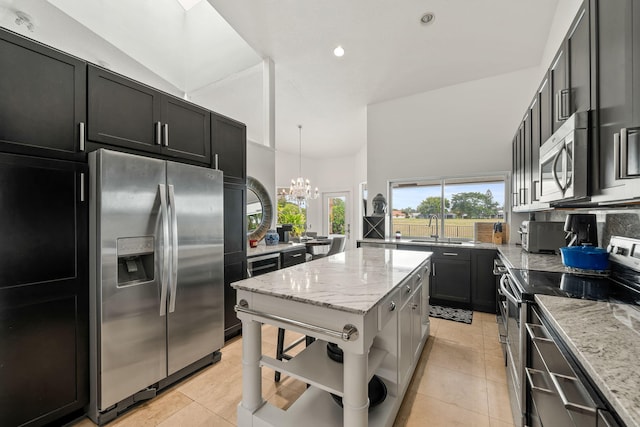 kitchen with stainless steel appliances, plenty of natural light, light stone counters, and decorative light fixtures