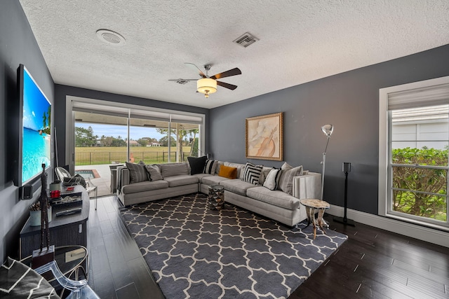 living room with ceiling fan, dark hardwood / wood-style floors, and a textured ceiling