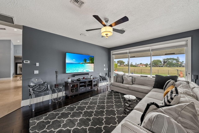 living room with hardwood / wood-style flooring, ceiling fan, and a textured ceiling