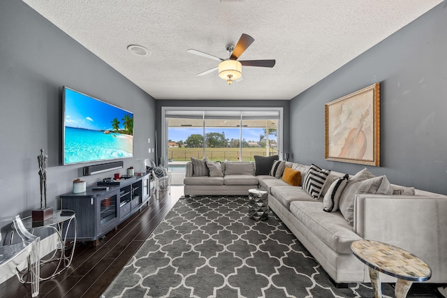 living room featuring a textured ceiling, dark wood-type flooring, and ceiling fan