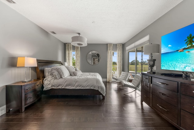 bedroom with access to exterior, dark hardwood / wood-style floors, and a textured ceiling