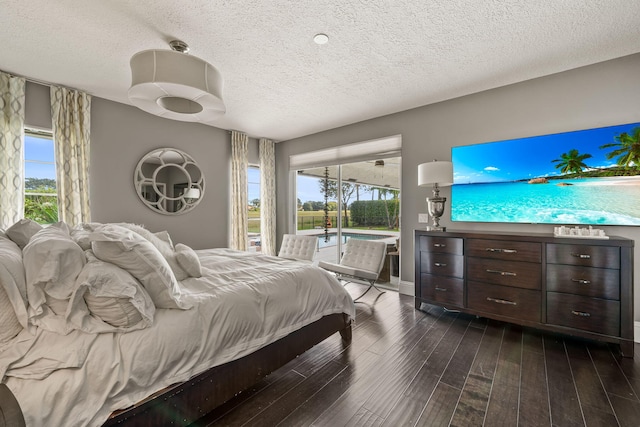 bedroom with access to exterior, dark hardwood / wood-style flooring, and a textured ceiling