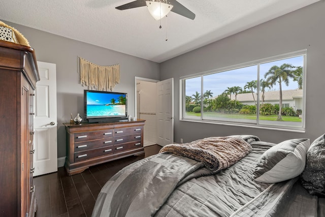 bedroom featuring dark wood-type flooring, ceiling fan, and a textured ceiling