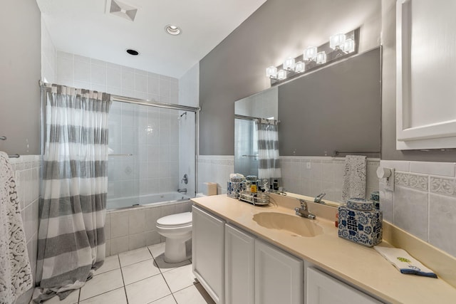 full bathroom featuring tile patterned flooring, tile walls, vanity, tiled shower / bath, and toilet