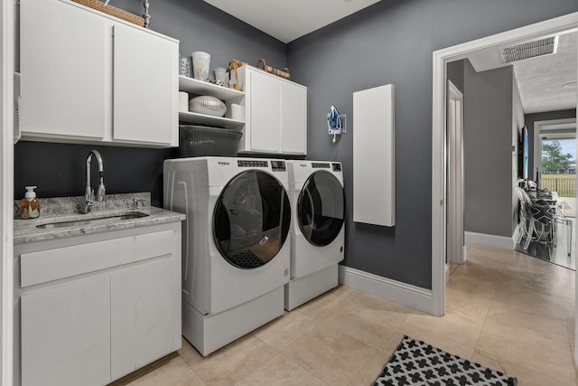 laundry room with sink, washing machine and dryer, and cabinets