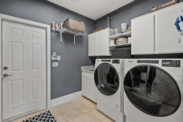 laundry room featuring washing machine and dryer, cabinets, and light tile patterned flooring