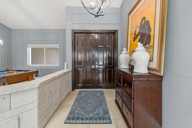 entryway with pool table, a notable chandelier, and light tile patterned floors