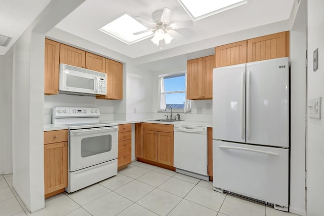 kitchen with a skylight, sink, light tile patterned floors, ceiling fan, and white appliances