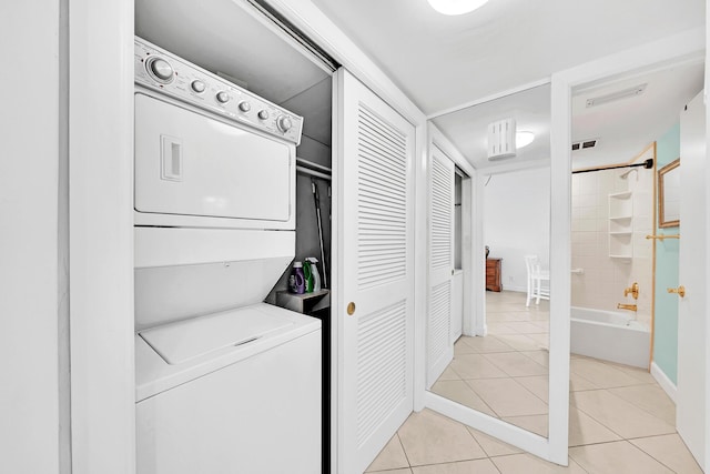 clothes washing area with stacked washer / dryer, laundry area, light tile patterned flooring, and visible vents