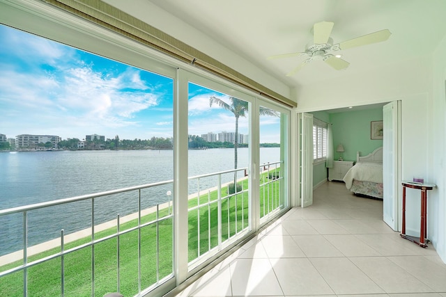 unfurnished sunroom with a water view, ceiling fan, and a city view