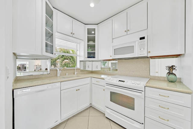 kitchen with white appliances, light countertops, a sink, and white cabinets