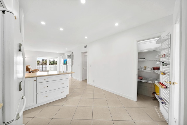 kitchen featuring light tile patterned floors, freestanding refrigerator, light countertops, white cabinetry, and recessed lighting