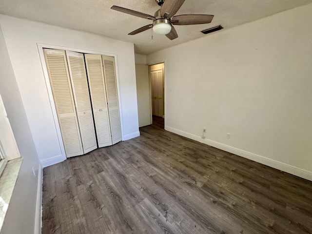 unfurnished bedroom with ceiling fan, a closet, wood-type flooring, and a textured ceiling