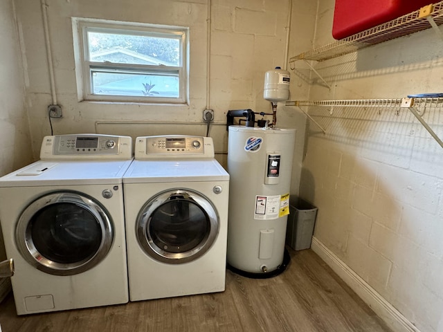 clothes washing area featuring electric water heater, separate washer and dryer, and hardwood / wood-style floors