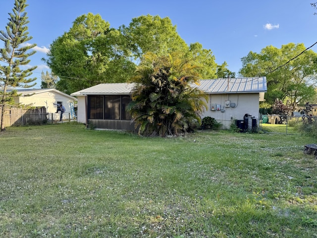 back of property with a sunroom and a lawn