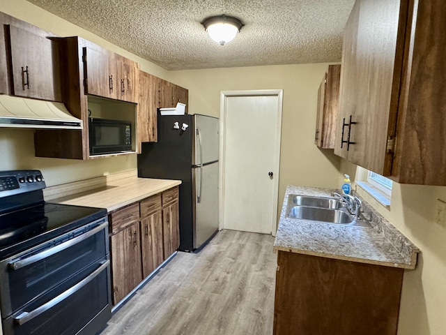 kitchen with light wood-type flooring, black appliances, ventilation hood, sink, and a textured ceiling