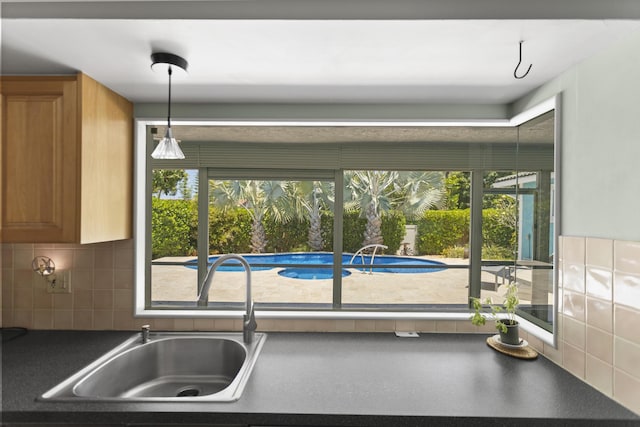 1821 N 50th Ave, Hollywood, FL 33021 - kitchen featuring a sink, dark countertops, tasteful backsplash, hanging light fixtures, and brown cabinets