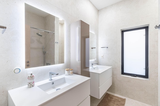 full bathroom featuring two vanities, tiled shower, and a sink