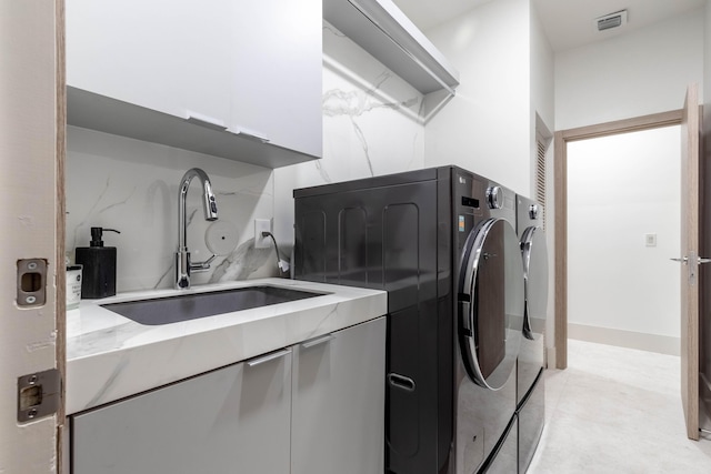 washroom with cabinet space, washing machine and dryer, visible vents, and a sink