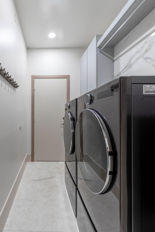 washroom with cabinet space, baseboards, and separate washer and dryer