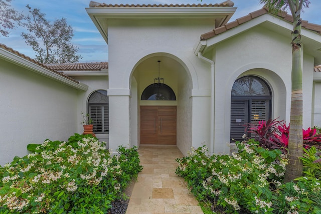 property entrance with a tile roof and stucco siding