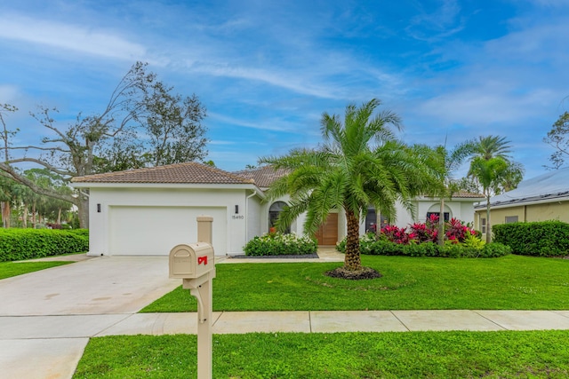 view of front facade with concrete driveway, a tile roof, an attached garage, a front yard, and stucco siding