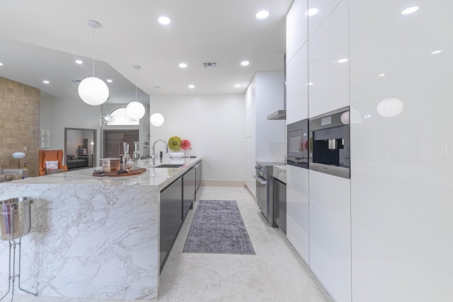 kitchen with light stone counters, visible vents, white cabinetry, a sink, and modern cabinets