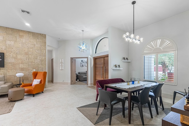 dining room with visible vents, an accent wall, a chandelier, and baseboards