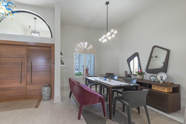 dining area featuring a notable chandelier, a towering ceiling, and baseboards