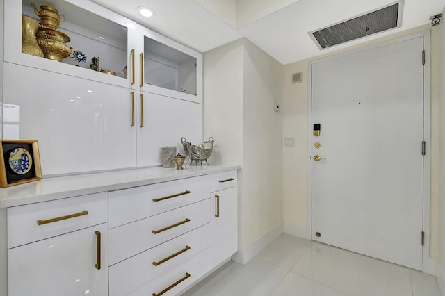 interior space with light tile patterned floors and white cabinets