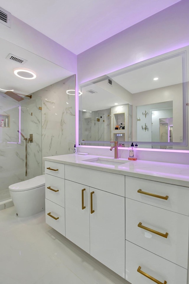 bathroom with vanity, toilet, and tiled shower