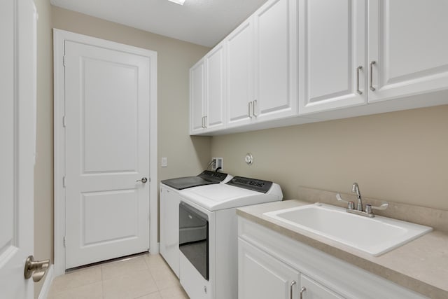 laundry room featuring washing machine and clothes dryer, light tile patterned flooring, a sink, and cabinet space