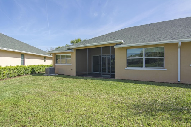 back of property with a sunroom, stucco siding, a lawn, and roof with shingles