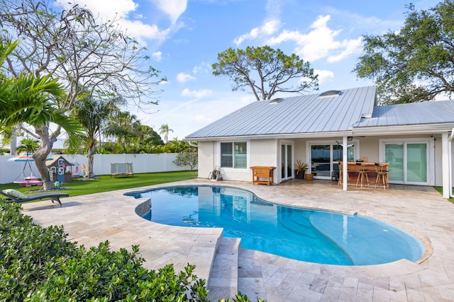 view of pool with a patio, exterior bar, and a lawn