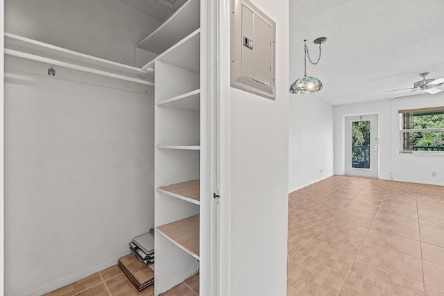 walk in closet with electric panel and a ceiling fan