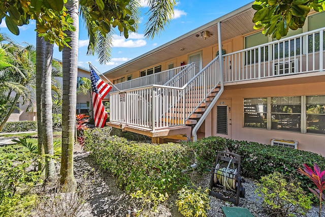 exterior space featuring covered porch, stucco siding, stairs, and a wall unit AC