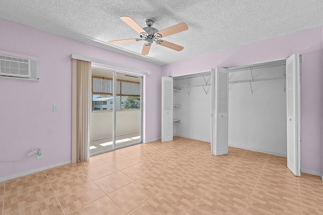 unfurnished bedroom featuring an AC wall unit, two closets, a textured ceiling, and a ceiling fan