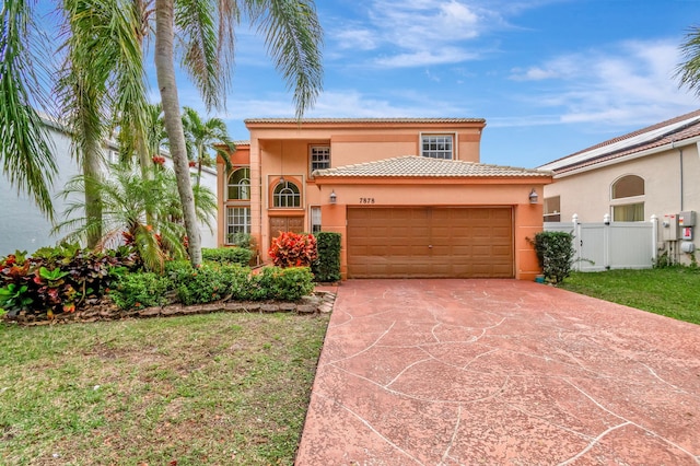 mediterranean / spanish home featuring an attached garage, fence, concrete driveway, stucco siding, and a front yard